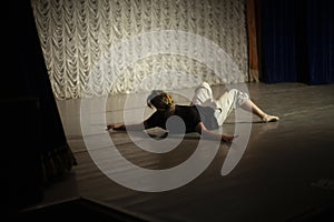 Dancer lies on stage. Ballerina shows movement. Dance lesson. Girl expresses pain