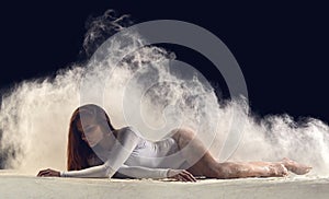 Dancer posing gracefully on the floor in a cloud of dust