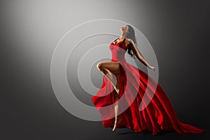 Dancer in Red Dress Jumping. Woman Ballerina Expressive Balance Dance Flying Fabric in Air. Fashion Model Dancing over Gray Studio