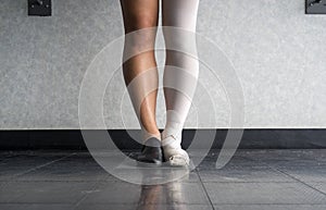 Dancer standing in parallel position at the barre, half dress in Jazz dance attire and half in ballet attire