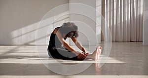 Dancer, stretching back and training legs, body or sitting on floor in yoga pose for warm up, mindfulness or meditation