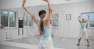 Dancer warms up infromt of the mirror wall in the white bright dance hall before rehearsal, ballet rehearsal, ballerina