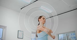 Dancer warms up before rehearsal in the white bright dance hall, ballet rehearsal, ballerina in the ballet studio, dance