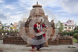 Dancer wears traditional red costume and posing at Mukteshvara Temple, Bhubaneswar, Odisha.