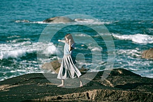 The dancer woman is engaged in choreography on the rocky Alantic coast.