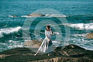 Dancer woman is engaged in choreography on the rocky Alantic coast.