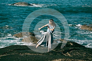 The dancer woman is engaged in choreography on the rocky Alantic ocean coast.