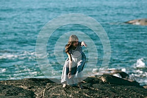 The dancer woman is engaged in choreography on the rocky Alantic ocean coast.