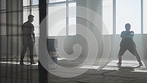 Dancers dancing in front of the large window in abandoned building. Teenagers making dance move simultaneously