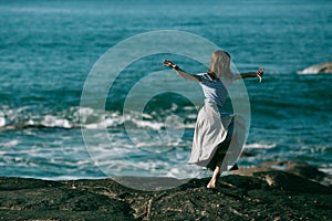 The dancers woman is engaged in choreography on the rocky coast of Atlantic ocean. Portugal.
