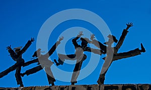 Dancing figurines against blue sky