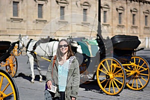 The girl stops in front of horses and carriages photo