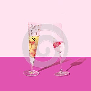 Dancing glasses posh concept. A glass of cocktail and a glass of champagne. Arrangement against purple and light pink