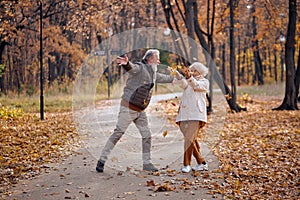 Dancing jumping in a park. Cheerful smiling senior man and woman having fun together