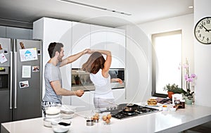 Dancing in the name of love. young couple dancing in the kitchen while preparing breakfast.