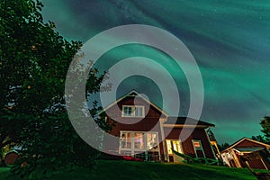 Dancing Northern lights Aurora borealis in autumn over wooden house in backyard. Umea town, Sweden, night. Copy space