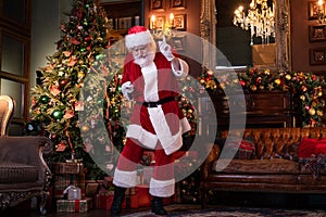 Dancing Santa preparing to congratulate children. Happy Santa Claus listening music and dancing at home near the