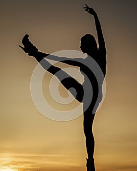 Dancing silhouette of woman ballet dancer in dusk on evening sky, ballerina