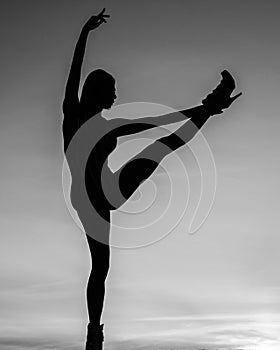 Dancing silhouette of woman ballet dancer in dusk on evening sky, ballerina