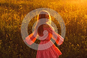 Dancing smiling beautiful girl in pink dress on field, sun backlight, sunrise