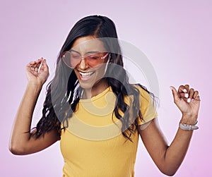 Dancing, sunglasses and cool woman excited, happy and confident isolated in a pink studio background with joy. Singing