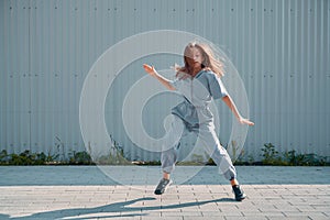 Dancing teen girl showing hip hop dance on urban background. Energetic young dancer cool moving on street