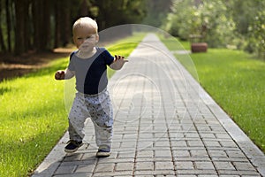 Dancing toddler in the park. First independent steps of cute one year baby boy