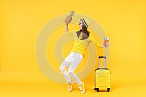 Dancing traveler tourist woman in hat holding passport tickets, fresh pineapple fruit isolated on yellow orange