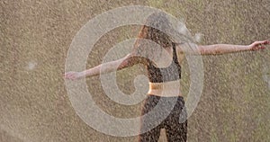 Dancing woman in the rain. The alluring young caucasian girl is having fun while spinning round and running outdoor.