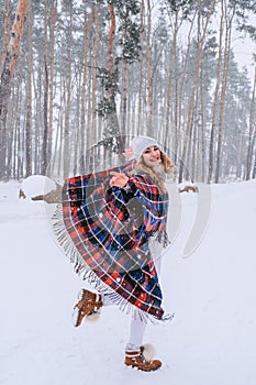 Dancing woman traveling among forest wearing hat and poncho, boho and wanderlust style. Winter is coming, first snowfall