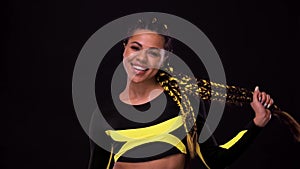 Dancing woman with yellow braids. Beautiful young woman on black background. Beauty shot in motion