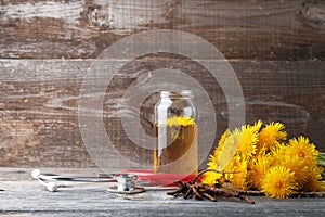 Dandelion broth in glass jar and  stethoscope on vintage wooden background with copy space, medicinal herbs, herbal medicine,