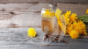 Dandelion broth in a glass jar on  vintage wooden background with copy space, medicinal herbs, herbal medicine, traditional