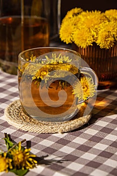 Dandelion flower healthy tea in glass teapot and glass cup on table. Delicious herbal Hot tea from fresh dandelion