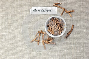 Dandelion herbal roots in a bowl flat from above on linen textile