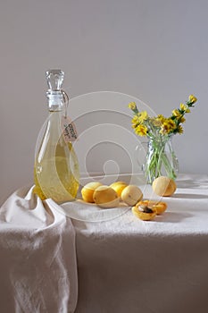Dandelion homemade wine in a glass bottle on table. Light background