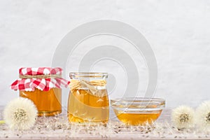 Dandelion jam, honey, jelly in a glass jar on a wooden table, white background with fresh flowers, dandelion airy seed