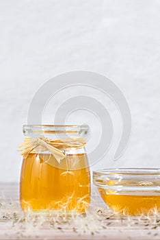 Dandelion jam, honey, jelly in a glass jar on a wooden table, white background with fresh flowers, dandelion airy seed