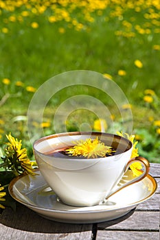 Dandelion tea in a white cup on a wooden table against a blurred