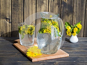 Dandelion tisane tea with fresh yellow blossom inside tea cup, on wooden table