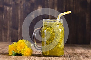 Dandelion yellow flower tea drink in glass mug on wooden table. Concept of healthy eating, herbal flower tincture