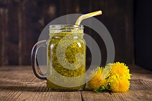 Dandelion yellow flower tea drink in glass mug on wooden table. Concept of healthy eating, herbal flower tincture