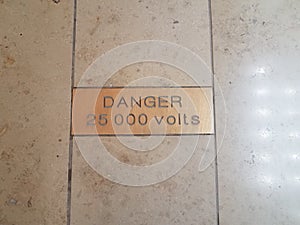 Danger 25000 volts warning sign on tile floor