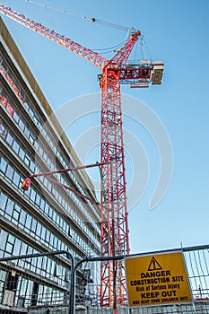 Danger construction site keep out sign with red crane over city