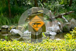 Danger crocodiles, no swimming - warning sign located on the shore of the lake. photo