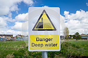 Danger Deep Water warning sign close up by rural waterway river stream.