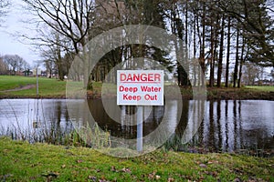 danger deep water warning sign by a water filled pond risk to the public