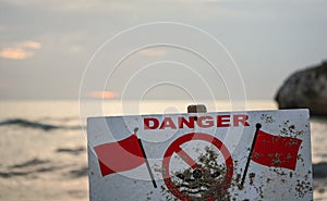 Danger do not swim sign with two red flags, blurred sea in background