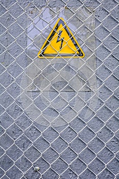 Danger of electrocution yellow sign on gray. High voltage warning sign