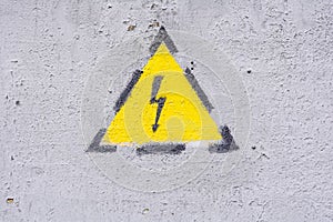 Danger of electrocution yellow sign on painted wall. High voltage warning sign